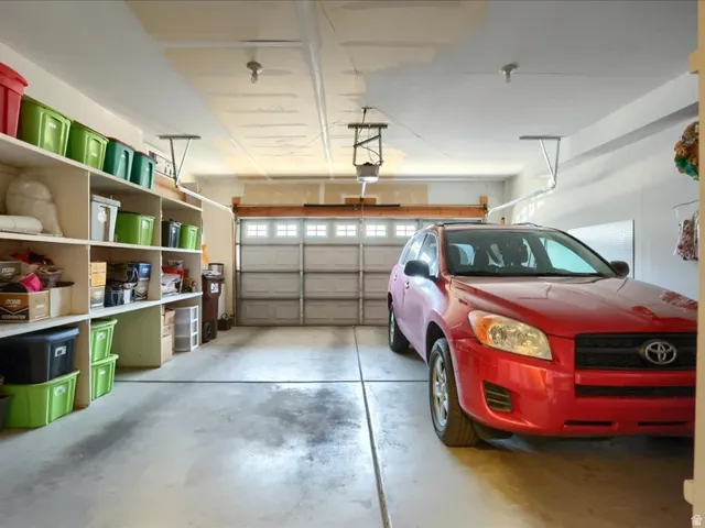 Two-car garage featuring concrete flooring, built-in shelving