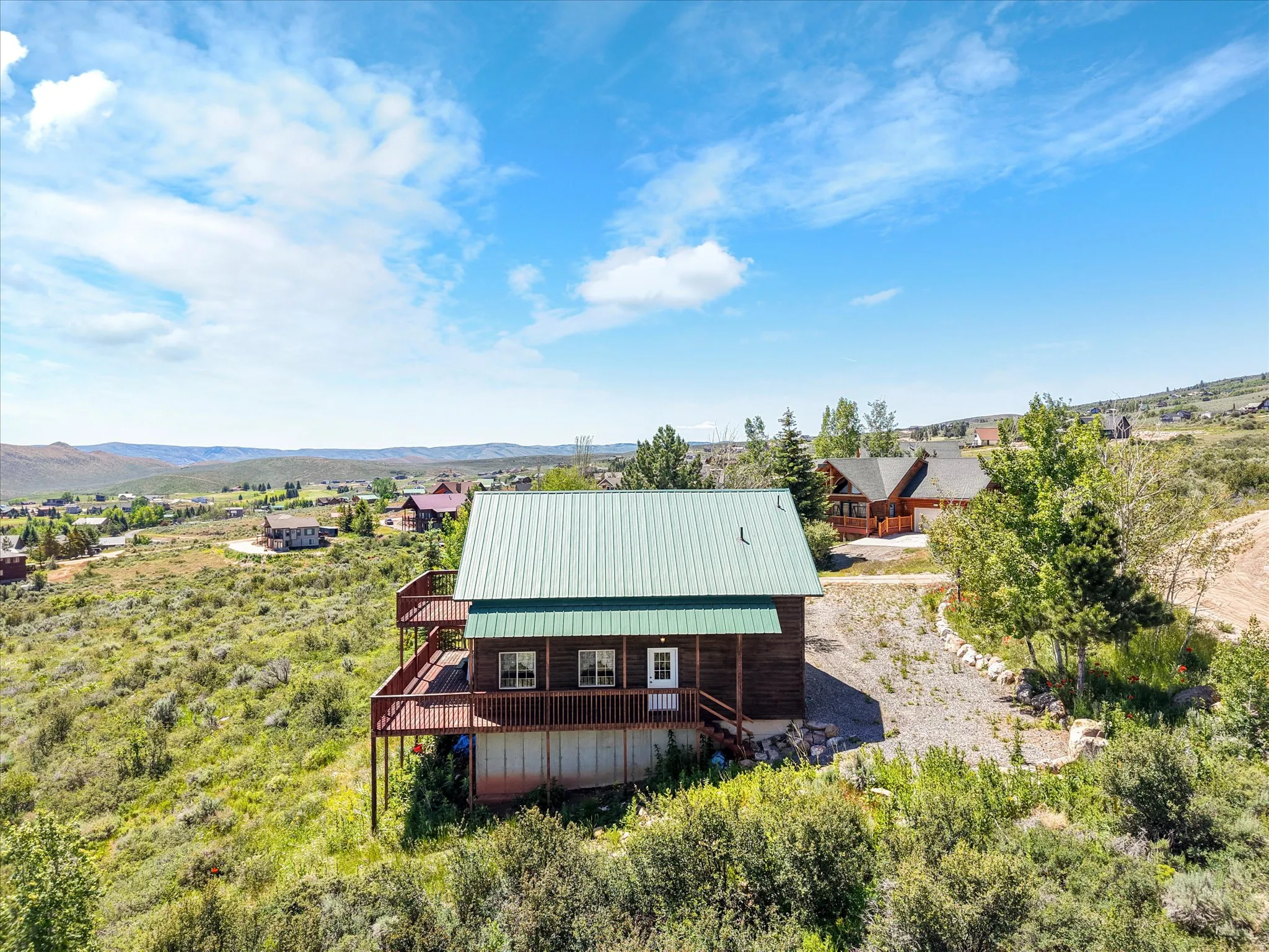 Wood-sided residence featuring a green metal roof and multiple exterior decks