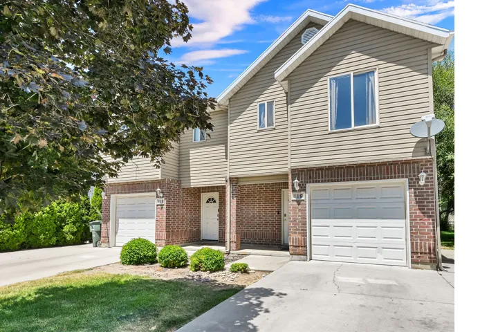 Townhome exterior featuring brick and siding facade, individual garage, and a concrete driveway