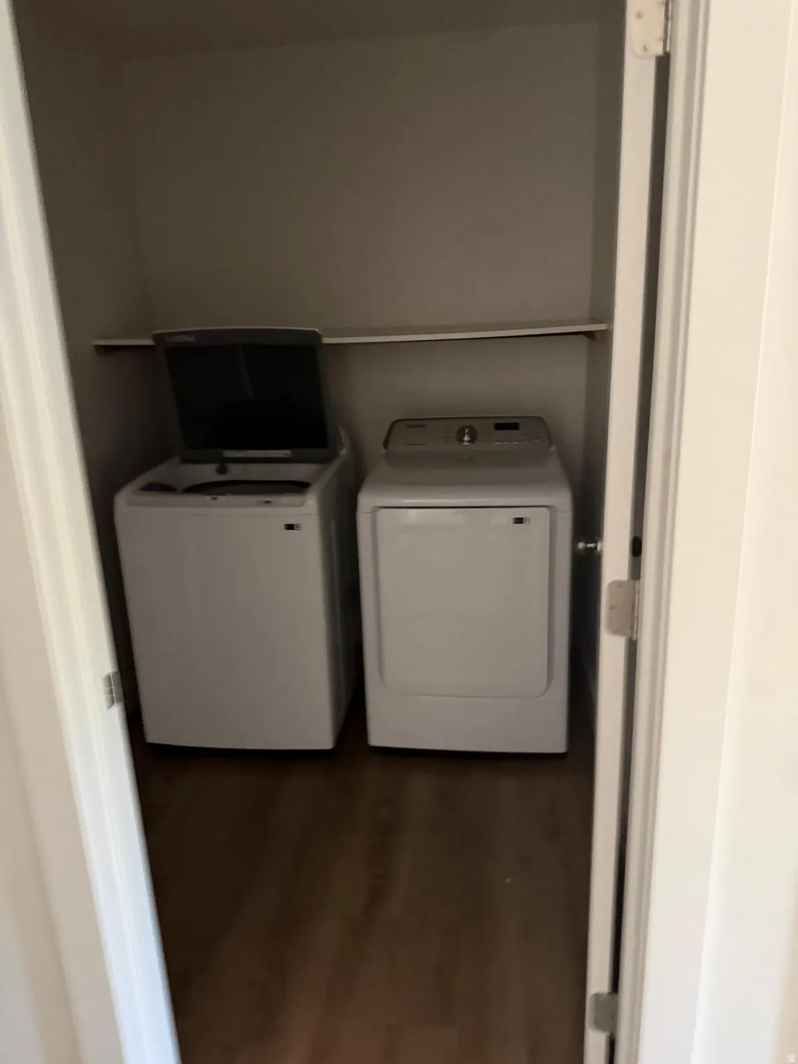 Dedicated laundry closet featuring a built-in shelf and wood-finish flooring