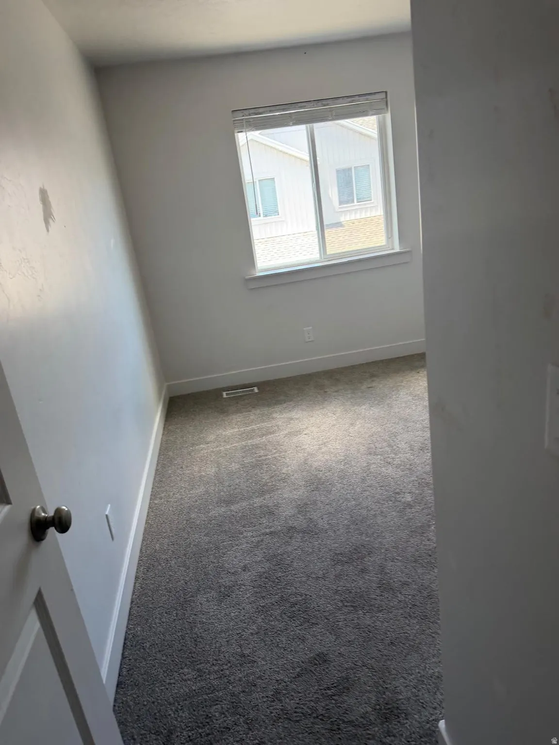 Room featuring light gray carpeting, neutral wall finishes, and a window with blinds