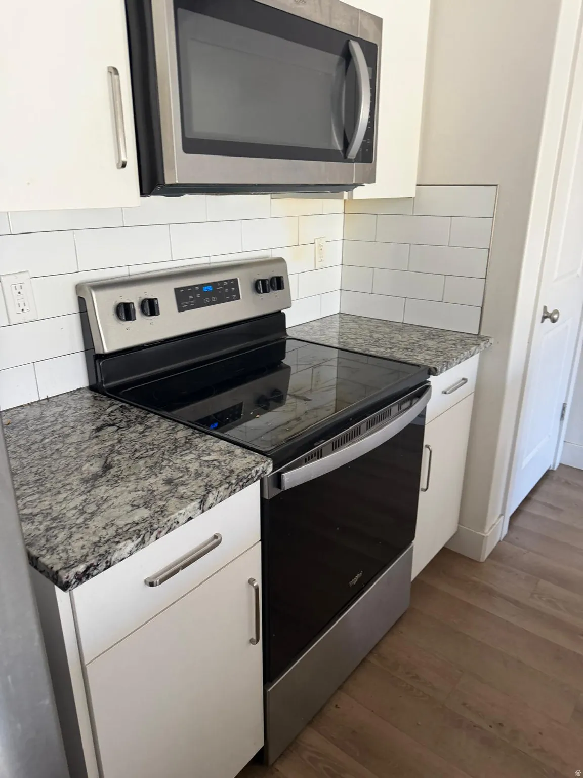 Stainless steel range with a smooth cooktop beneath an over-the-range microwave