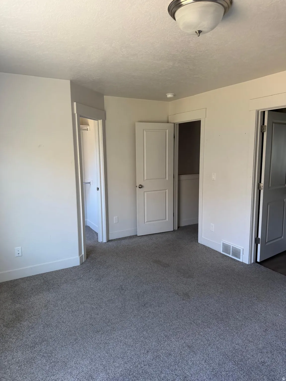 Gray wall-to-wall carpeting in an interior room with white trim and multiple doors
