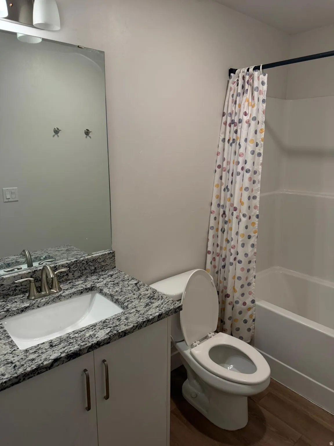 Bathroom vanity featuring a rectangular undermount sink, brushed nickel faucet, and a granite-finish countertop