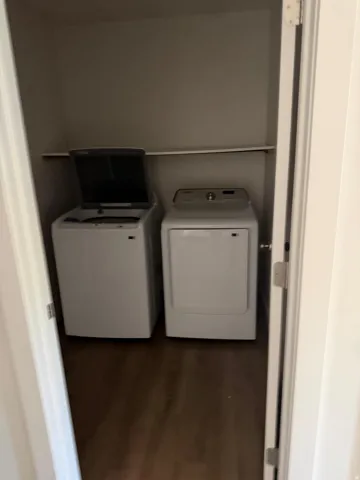 Dedicated laundry closet featuring a built-in shelf and wood-finish flooring