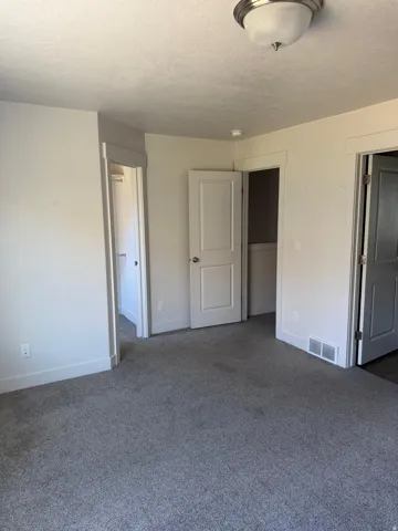 Gray wall-to-wall carpeting in an interior room with white trim and multiple doors