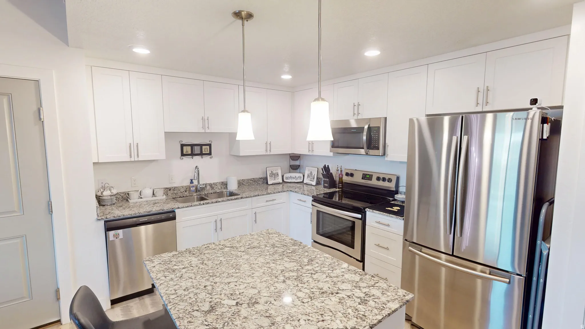 Contemporary kitchen featuring white shaker cabinetry, stainless steel appliances, a granite-topped island, and recessed lighting