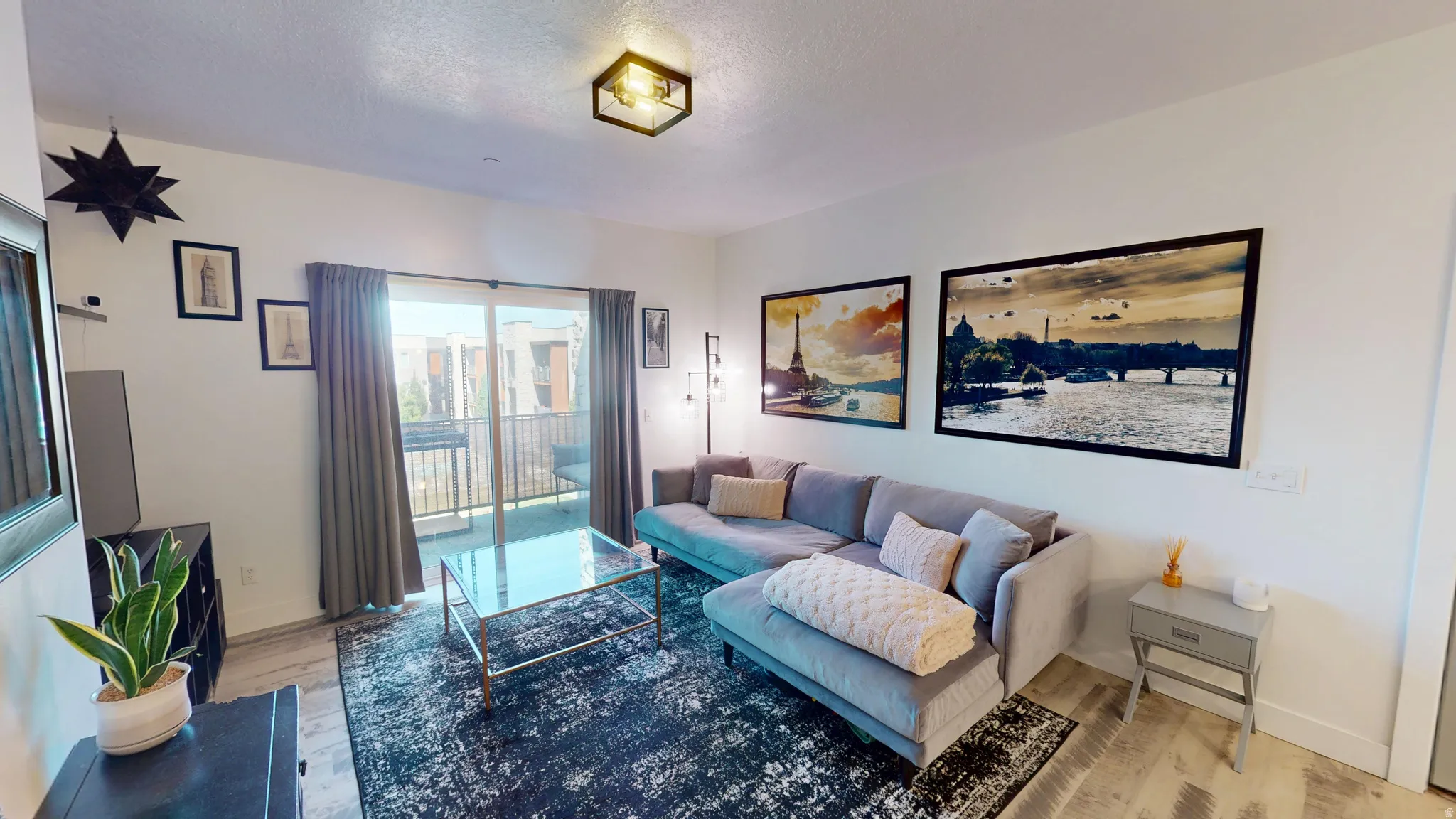 Open-concept living area featuring light wood-finish flooring and a contemporary overhead light fixture