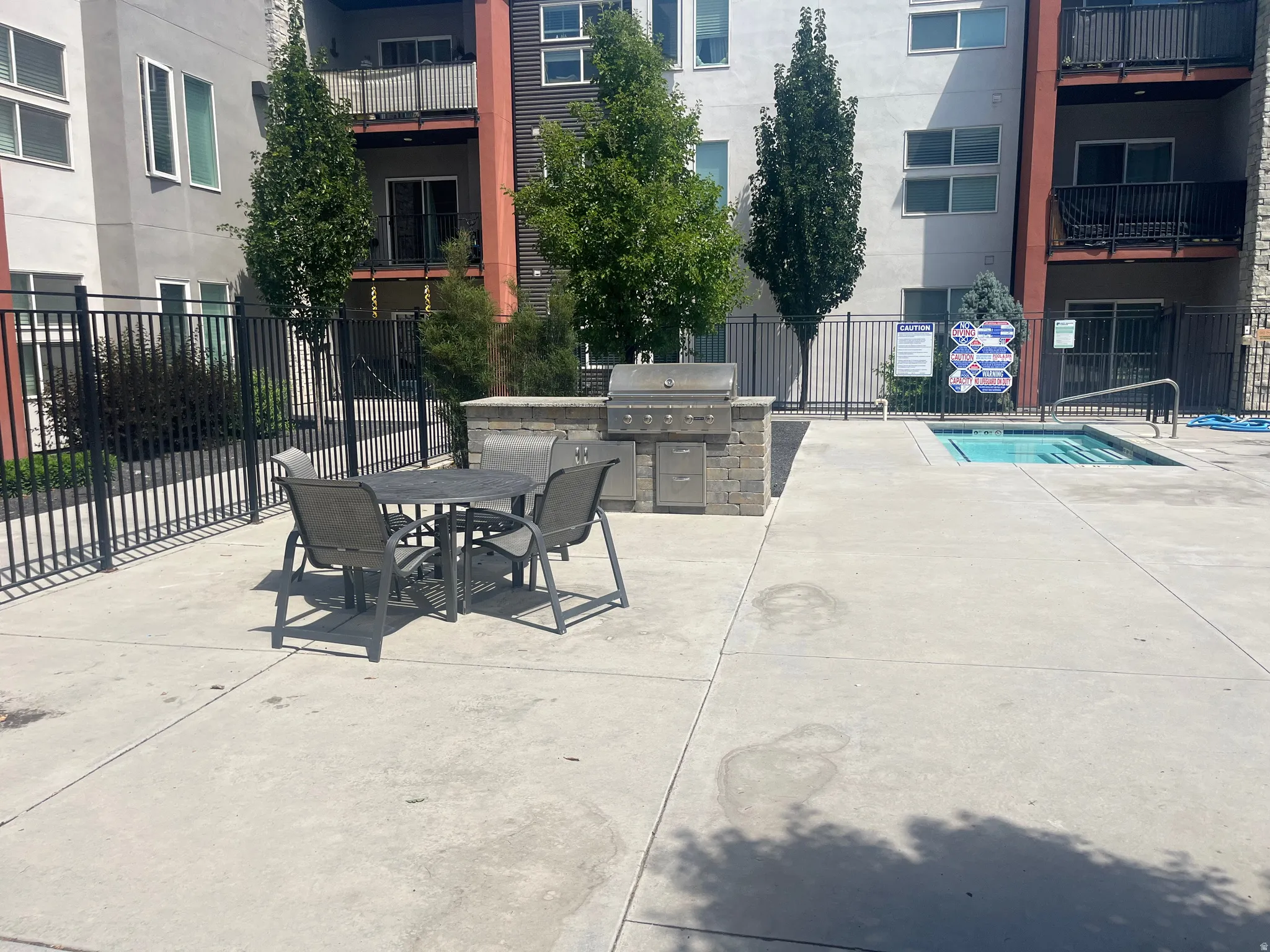 Outdoor patio area featuring a built-in barbecue grill with stone surround, a separate water feature, and a concrete patio surface