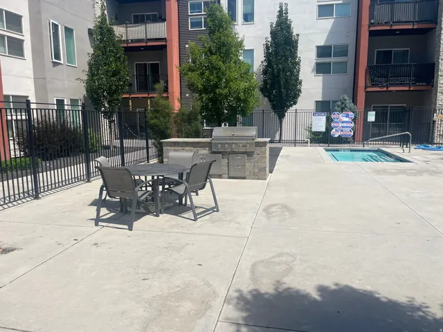 Outdoor patio area featuring a built-in barbecue grill with stone surround, a separate water feature, and a concrete patio surface
