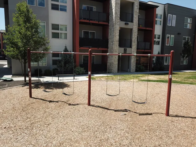 Outdoor play area featuring a swing set with four swings, set over wood chip surfacing