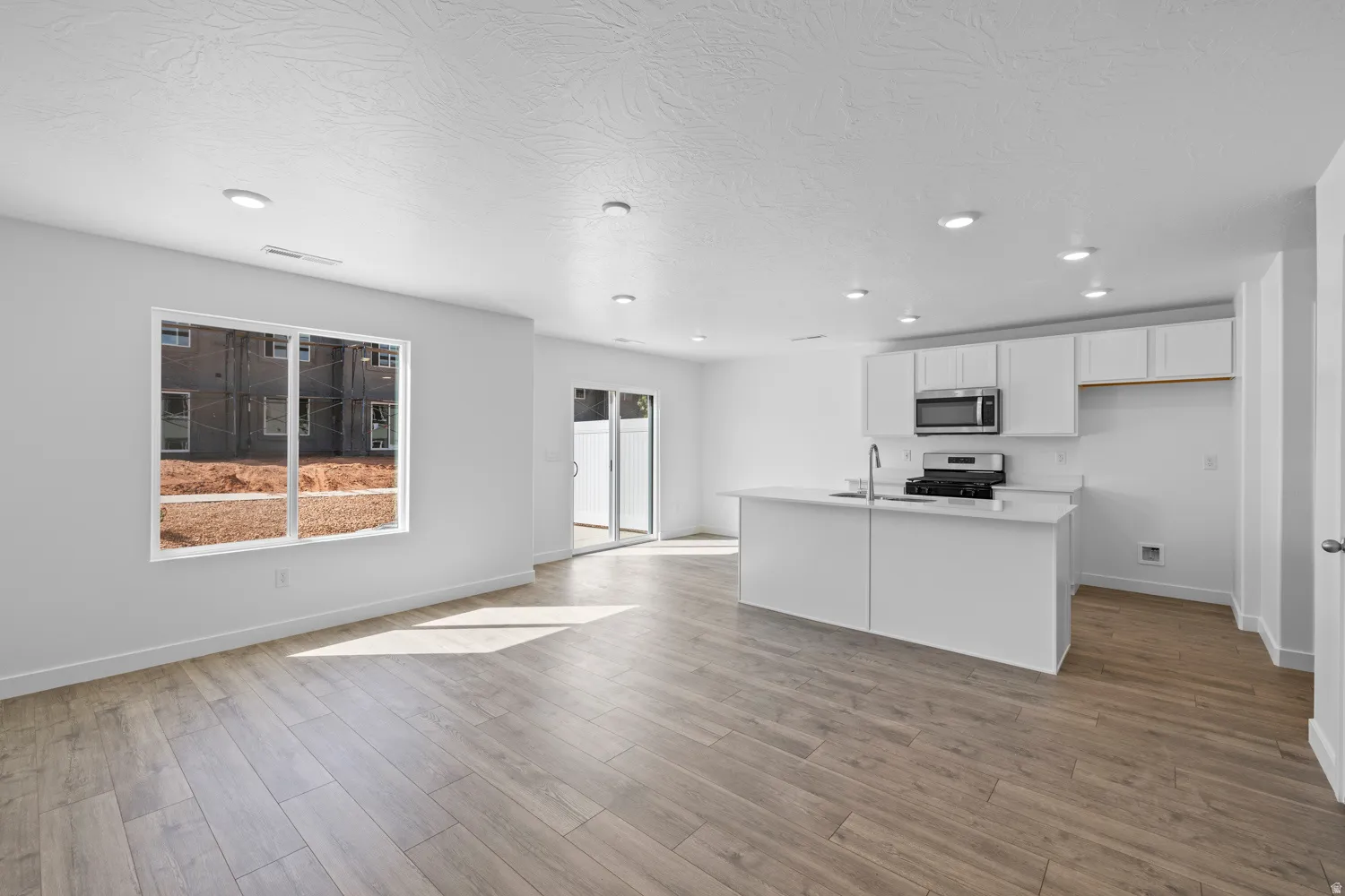 Open-concept living area featuring wood-finish flooring, recessed lighting, and white walls
