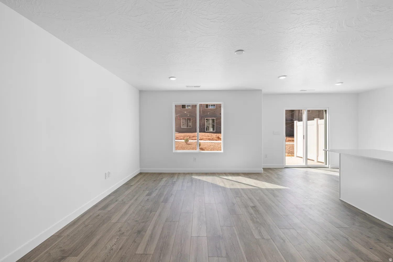 Open-concept living space with wood-finish flooring, recessed lighting, and a sliding glass door leading to the exterior