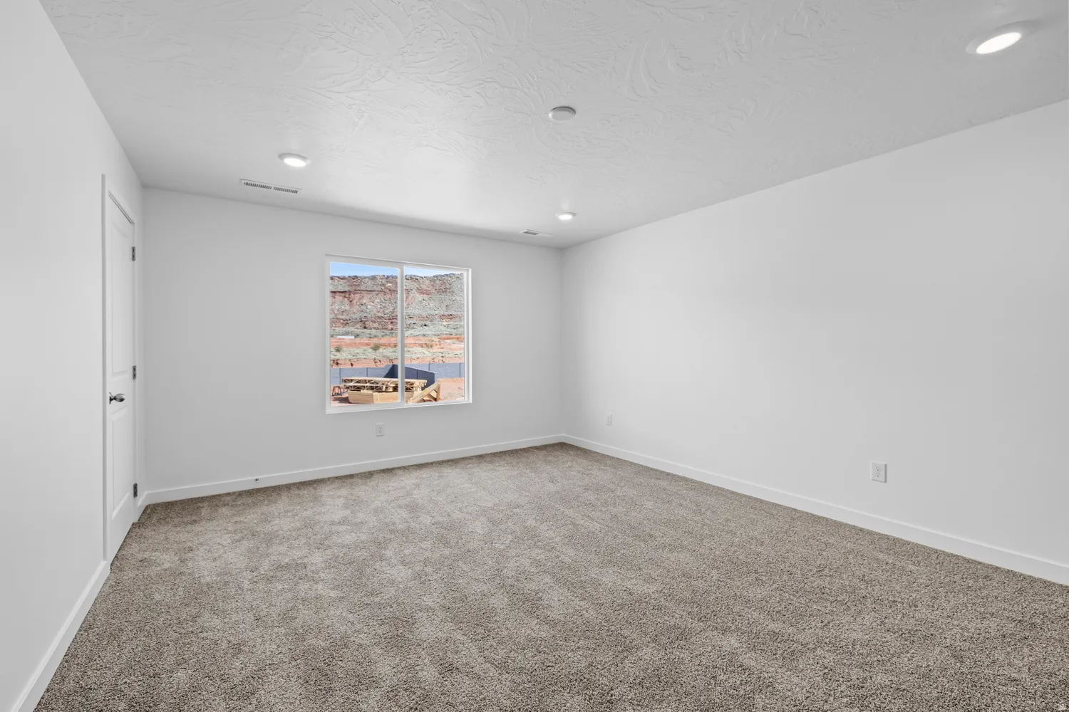 Spacious interior room featuring plush gray carpeting and white painted walls