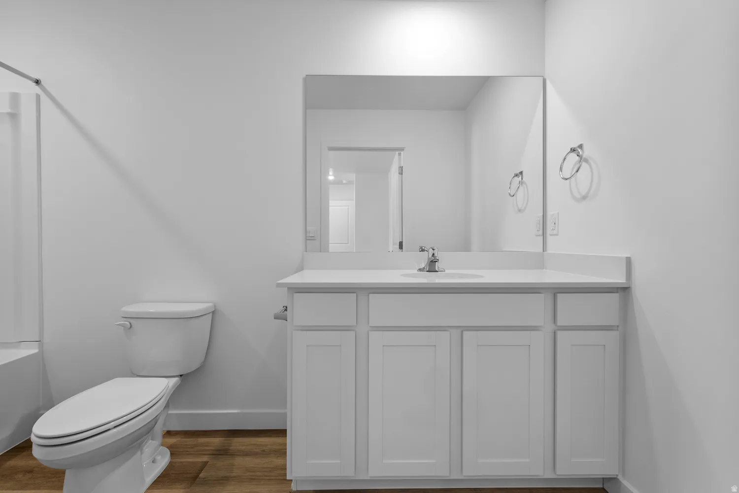 White vanity with shaker-style cabinetry, an integrated sink, and a large mirror