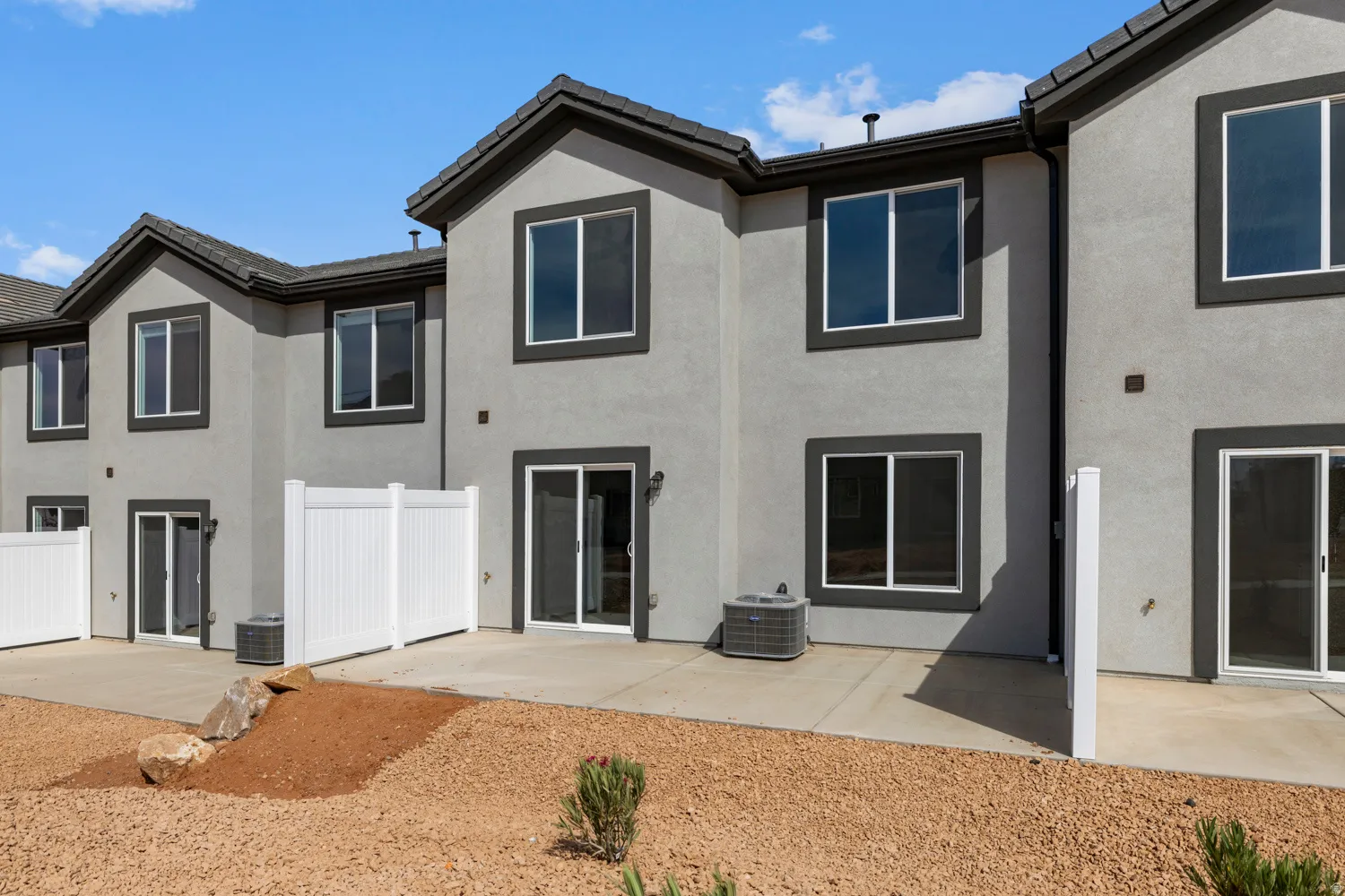 Rear exterior featuring stucco finish, dark trim windows, and sliding glass doors