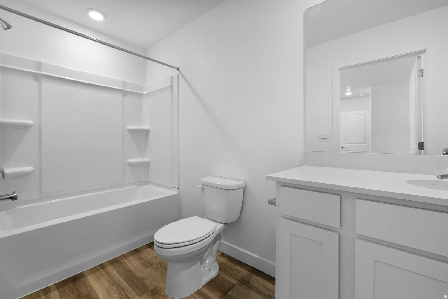 Bathroom featuring a white vanity with an integrated sink, a rectangular mirror, and a toilet