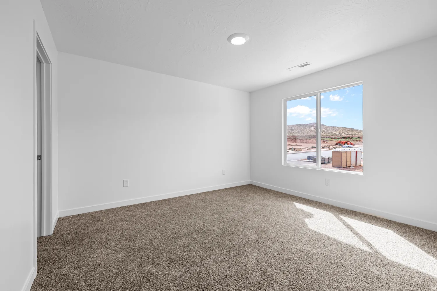 Spacious room featuring neutral carpeting and white walls