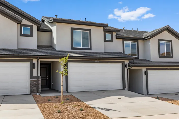Modern stucco exterior with dark trim accents and a stone veneer base