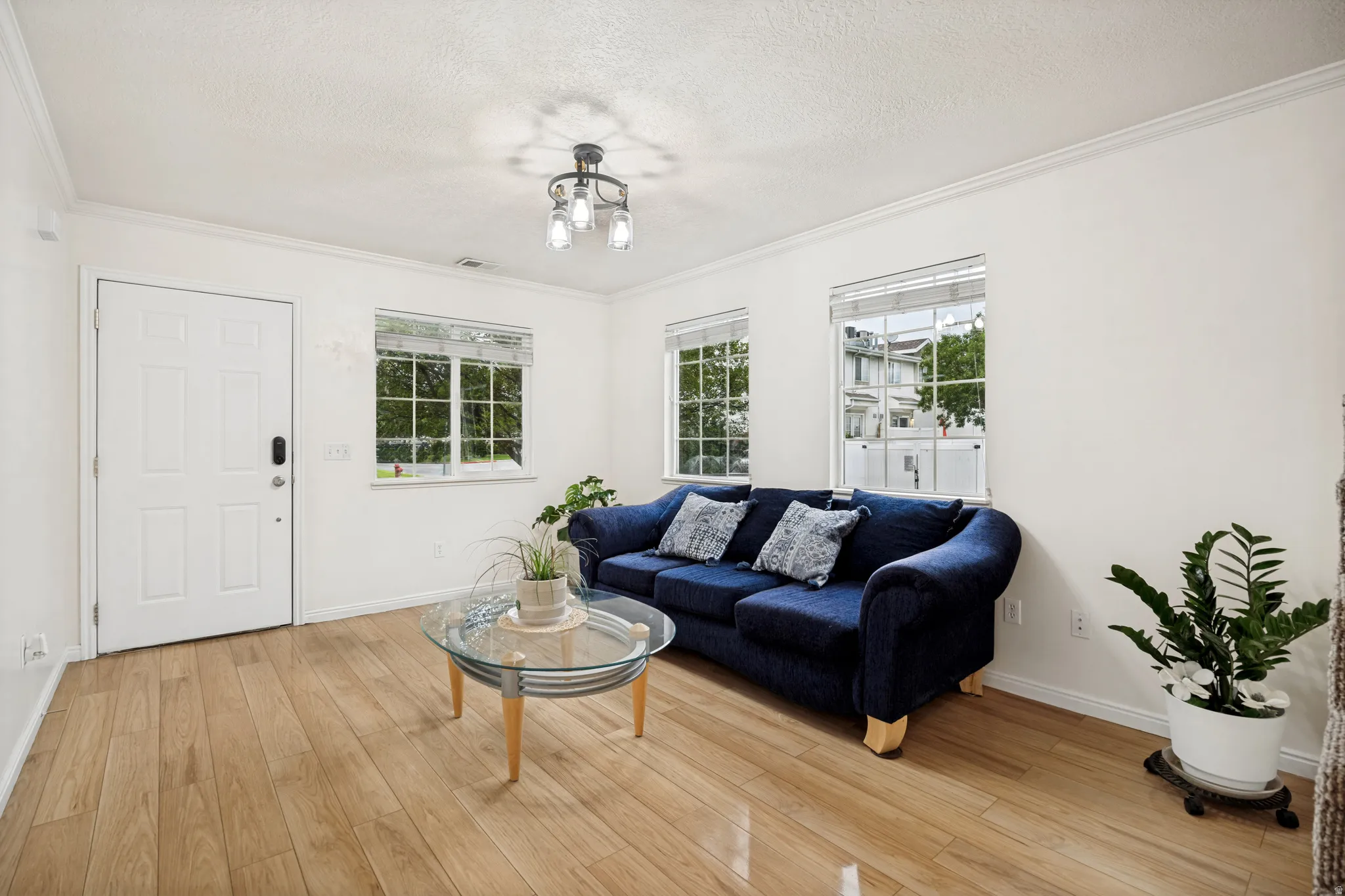 Living space featuring light wood-finish flooring, white walls, and crown molding