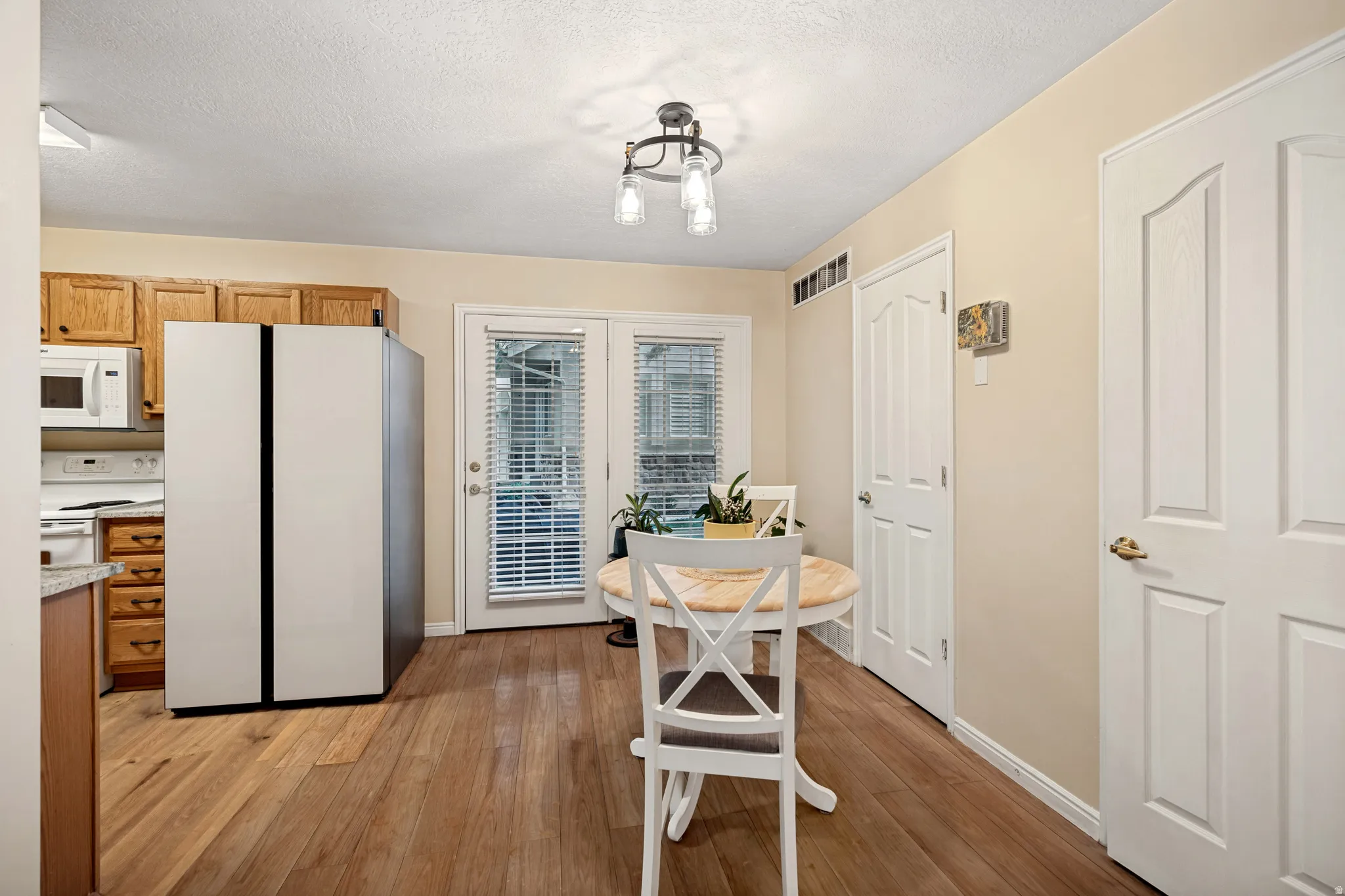 Kitchen area featuring wood-finish flooring, light wood cabinetry, and a double-door exterior entry
