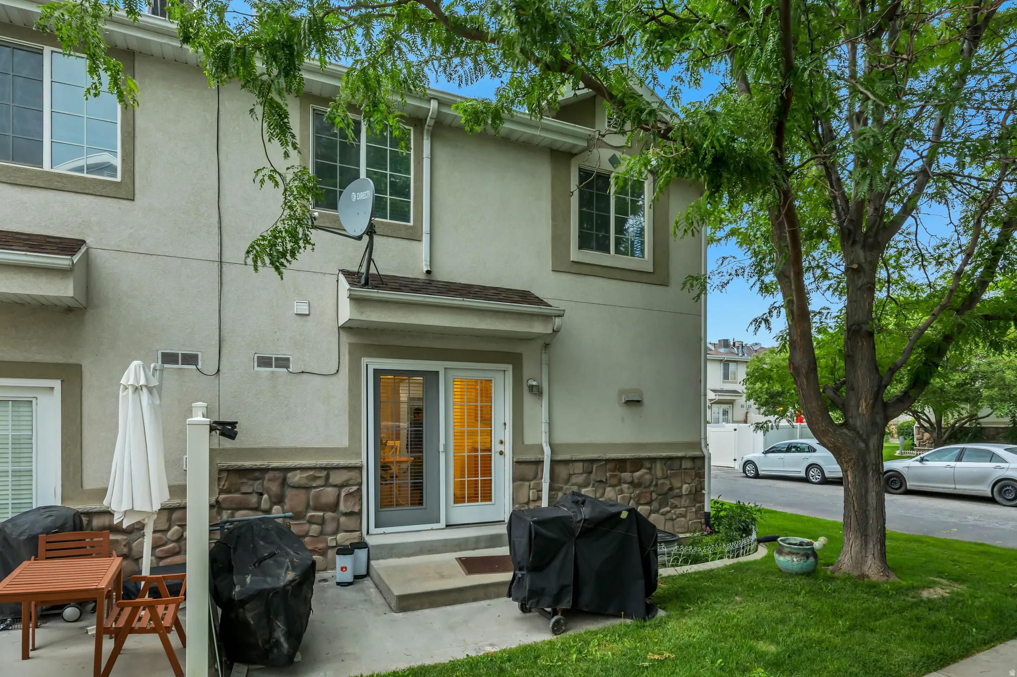 Rear exterior featuring a stone accent wall, stucco siding, and a concrete patio
