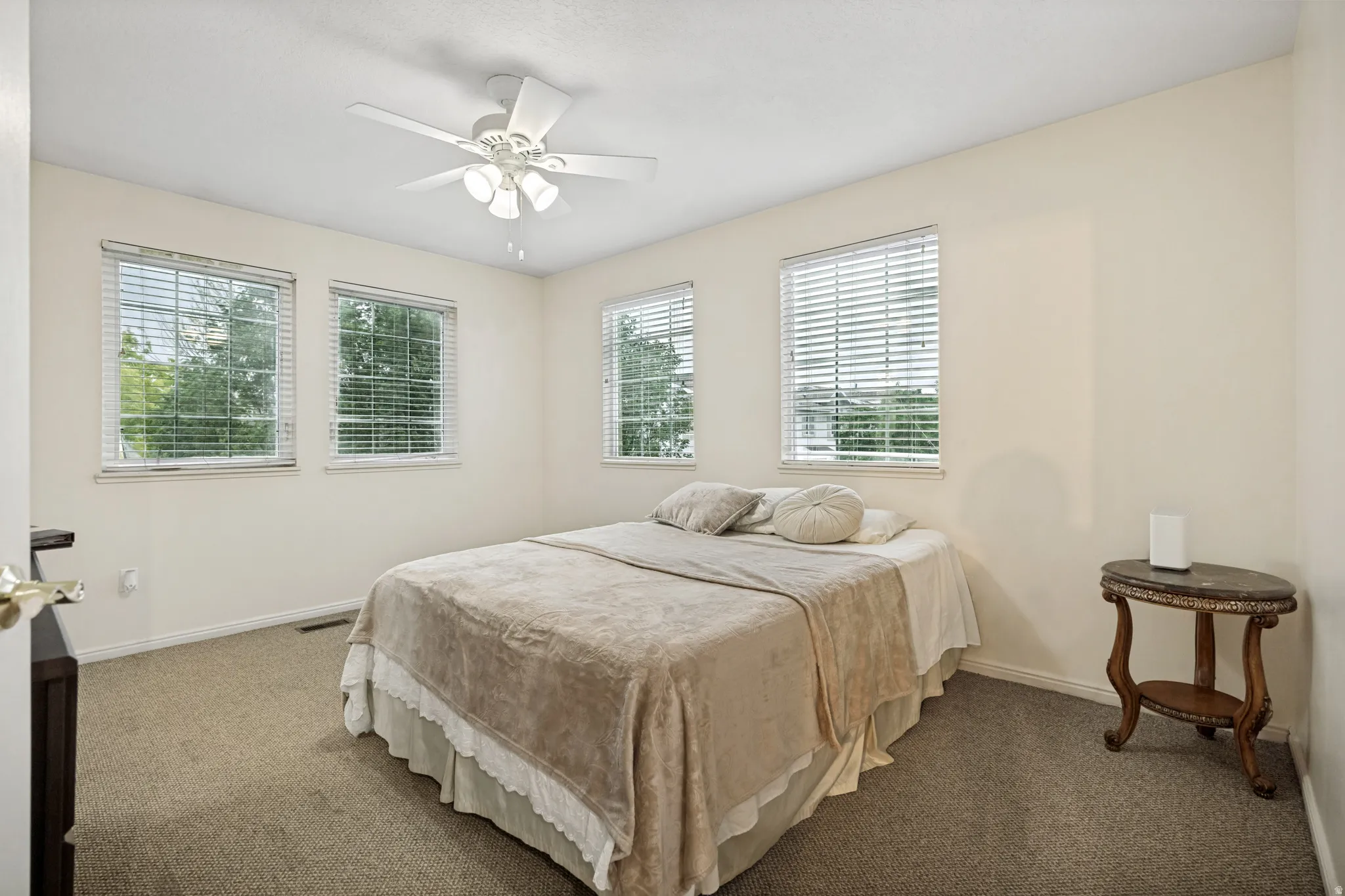 Bedroom featuring carpet flooring, multiple windows with blinds, and a ceiling fan with integrated lighting
