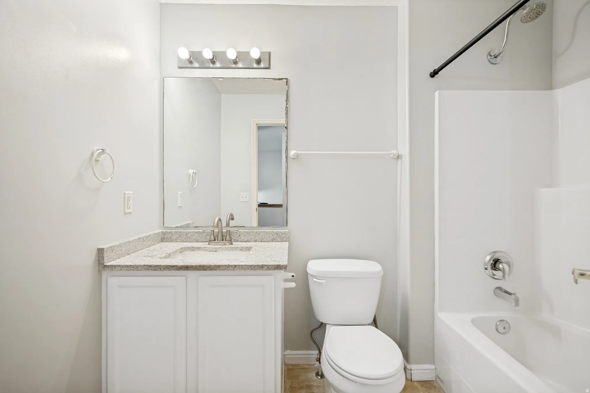 Bathroom vanity featuring a light-toned countertop with integrated sink, brushed nickel faucet, and a mirror with overhead lighting