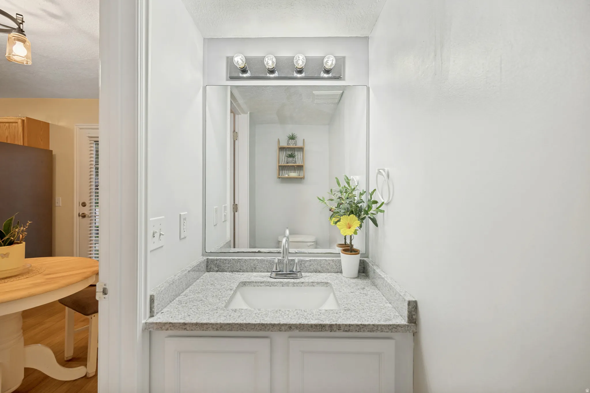 White vanity with a light-toned speckled countertop and undermount sink