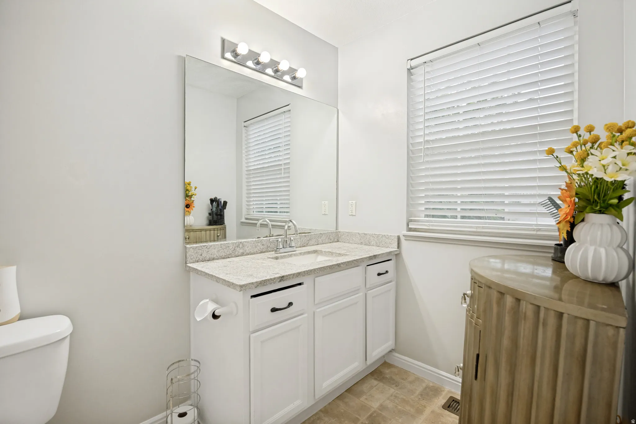 Bathroom vanity with a light-toned countertop, undermount sink, and chrome faucet