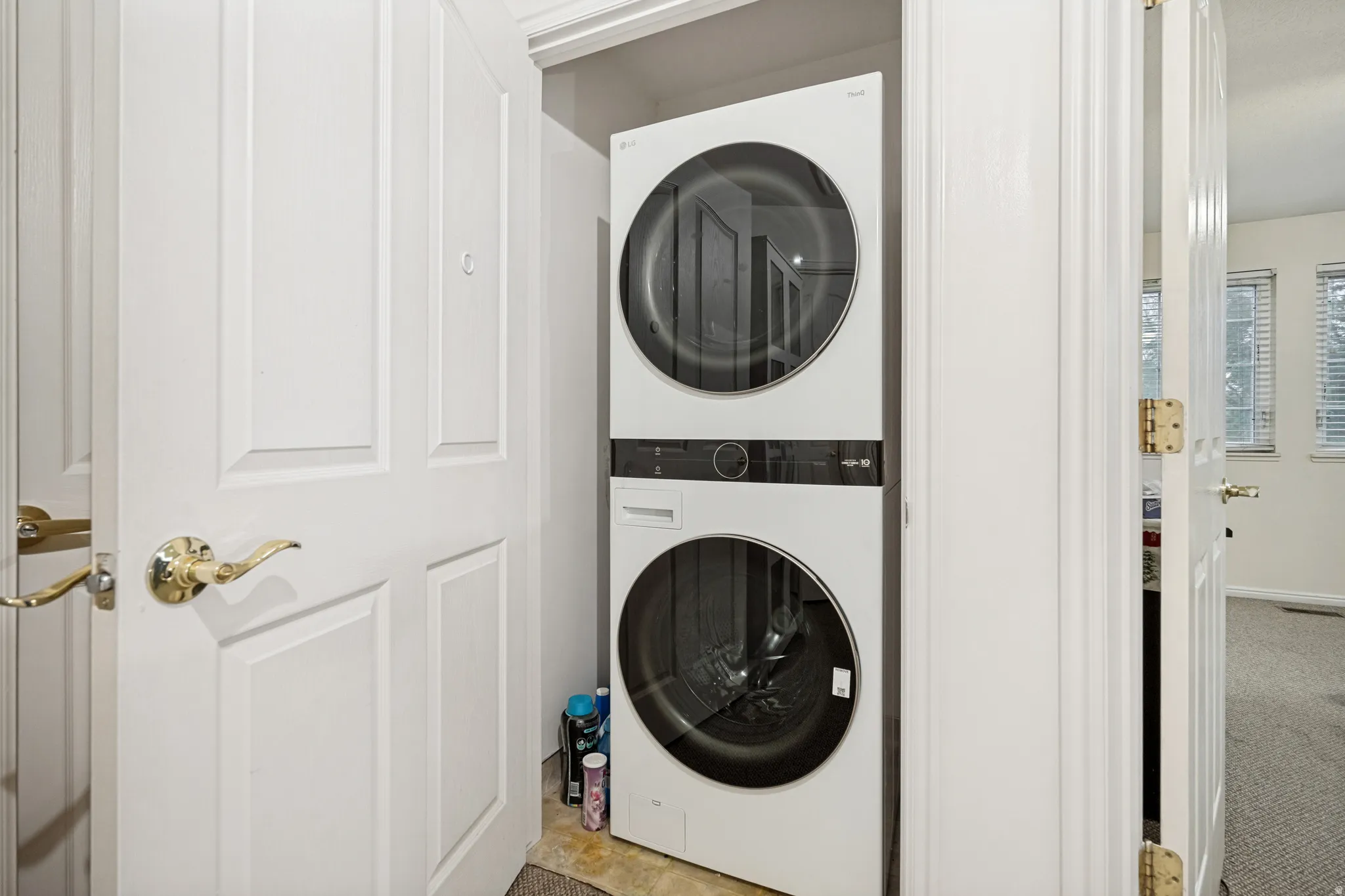 Dedicated laundry closet featuring a stacked white washer and dryer unit