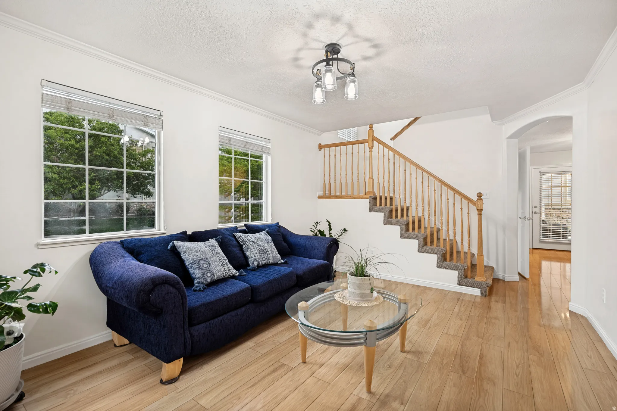 Light wood-finish flooring throughout the room with a carpeted staircase featuring a natural wood railing