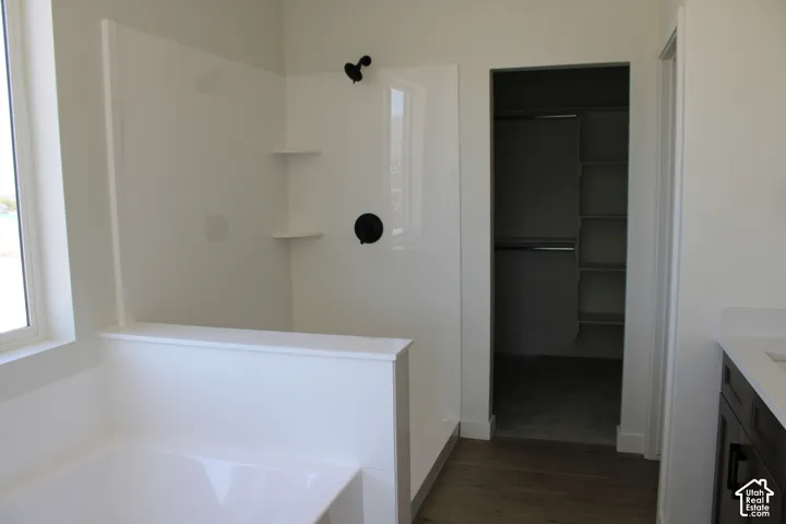 White bathtub and shower combination featuring matte black fixtures and built-in shelving