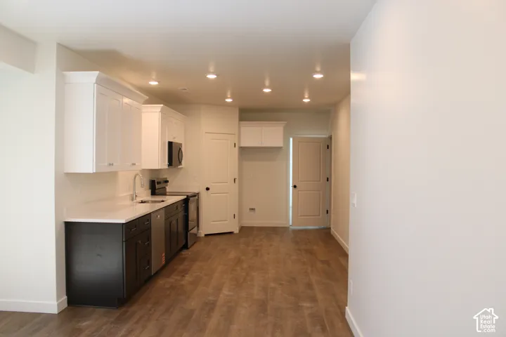 ADU Kitchen featuring two-tone cabinetry with white upper and dark lower cabinets, stainless steel appliances, and wood-finish flooring