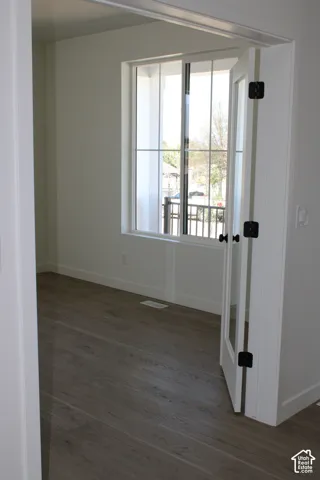 Room with wood-finish flooring, white baseboards, and neutral wall paint