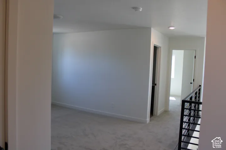 Carpeted hallway featuring recessed lighting, a modern black metal railing, and white trim