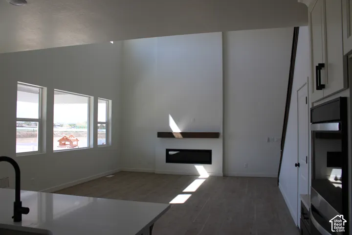 Open-concept living area featuring a vaulted ceiling, three large windows, and wood-finish flooring