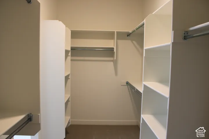 Walk-in closet featuring built-in white shelving, multiple hanging rods, and neutral-toned carpeting