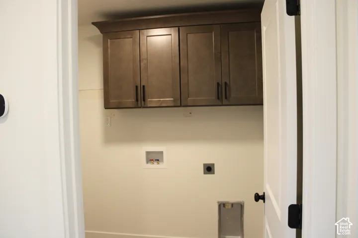 Utility space featuring upper wood cabinetry with black hardware, white walls, and baseboard molding