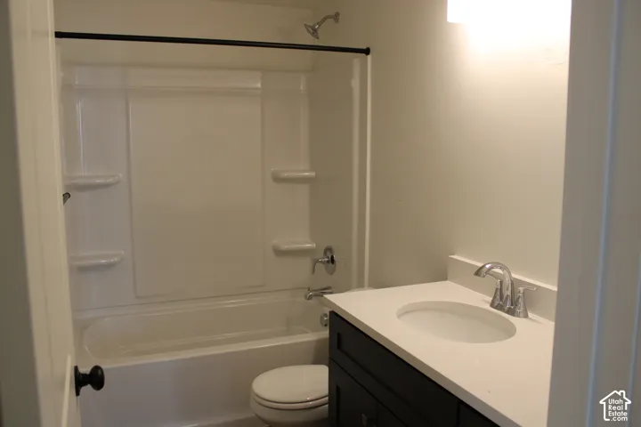 ADU Bathroom featuring a white tub-shower combination, dark wood-finish vanity with a light-toned countertop, integrated sink, and chrome fixtures