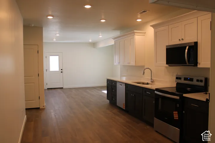 ADU Open-concept kitchen featuring two-tone cabinetry, stainless steel appliances, a built-in microwave, and wood-finish flooring