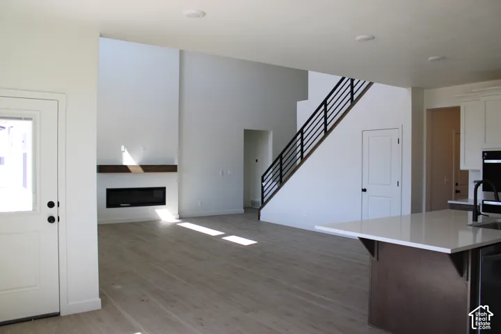 Open-concept living area featuring high ceilings, wood-finish flooring, and a modern fireplace with a wood mantle