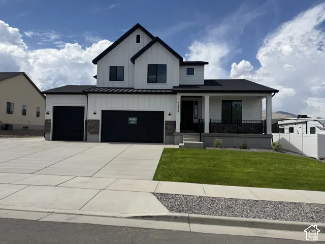 Contemporary two-story residence with a covered porch, attached two-car garage, and an additional single-car garage