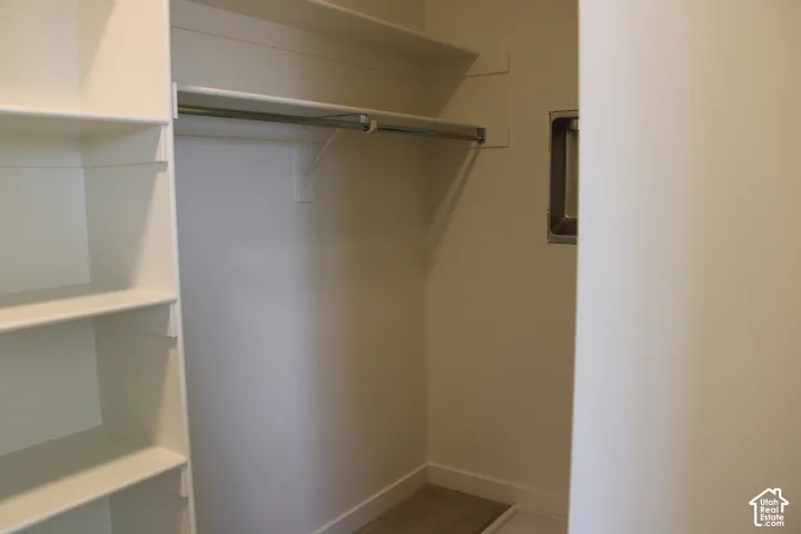 Walk-in closet featuring built-in shelving, two clothing rods, and a wall vent