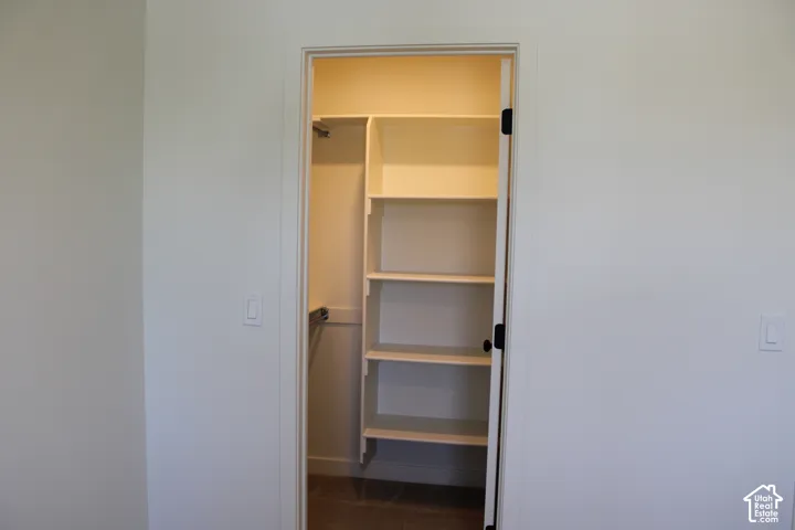 Walk-in closet featuring built-in shelving, hanging rods, and wood-finish flooring
