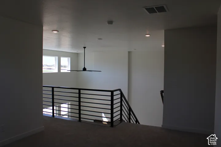 Upper-level landing featuring a modern horizontal metal railing system and a ceiling fan