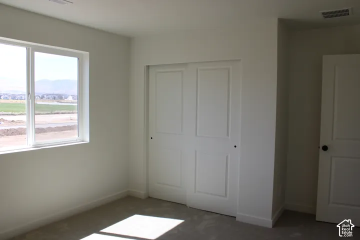 Clean, neutral-toned interior space featuring a large window, white trim, and light-colored carpeting