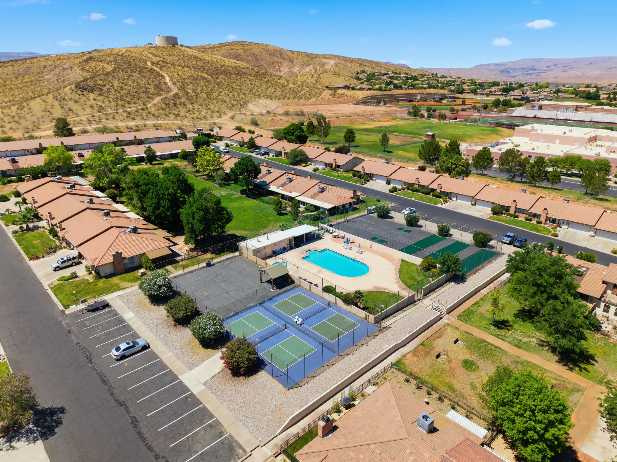 Aerial perspective showcasing multiple residential units, a community swimming pool, and two tennis courts