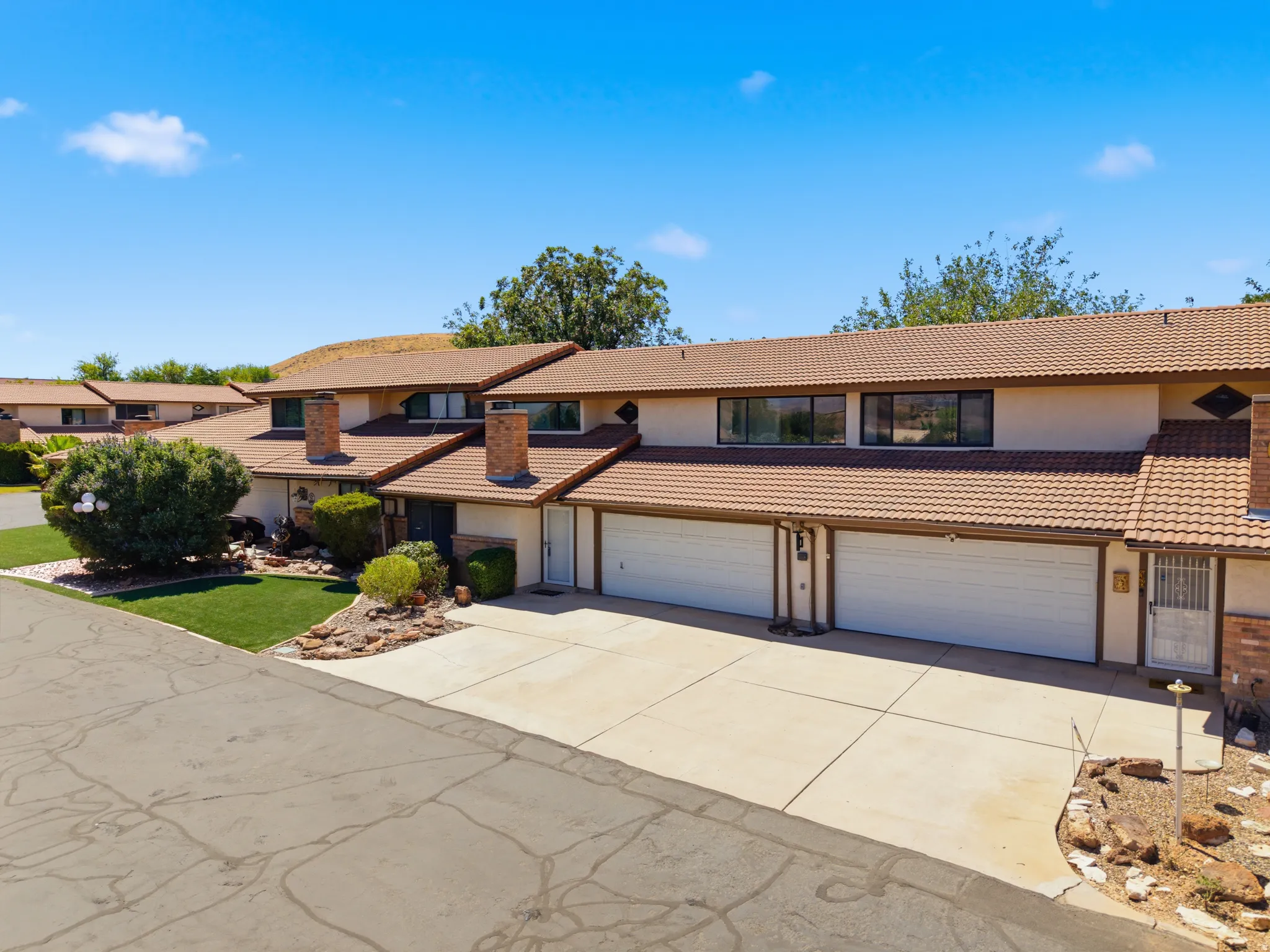 Townhome exterior featuring a tile roof, dual garages, and a paved driveway