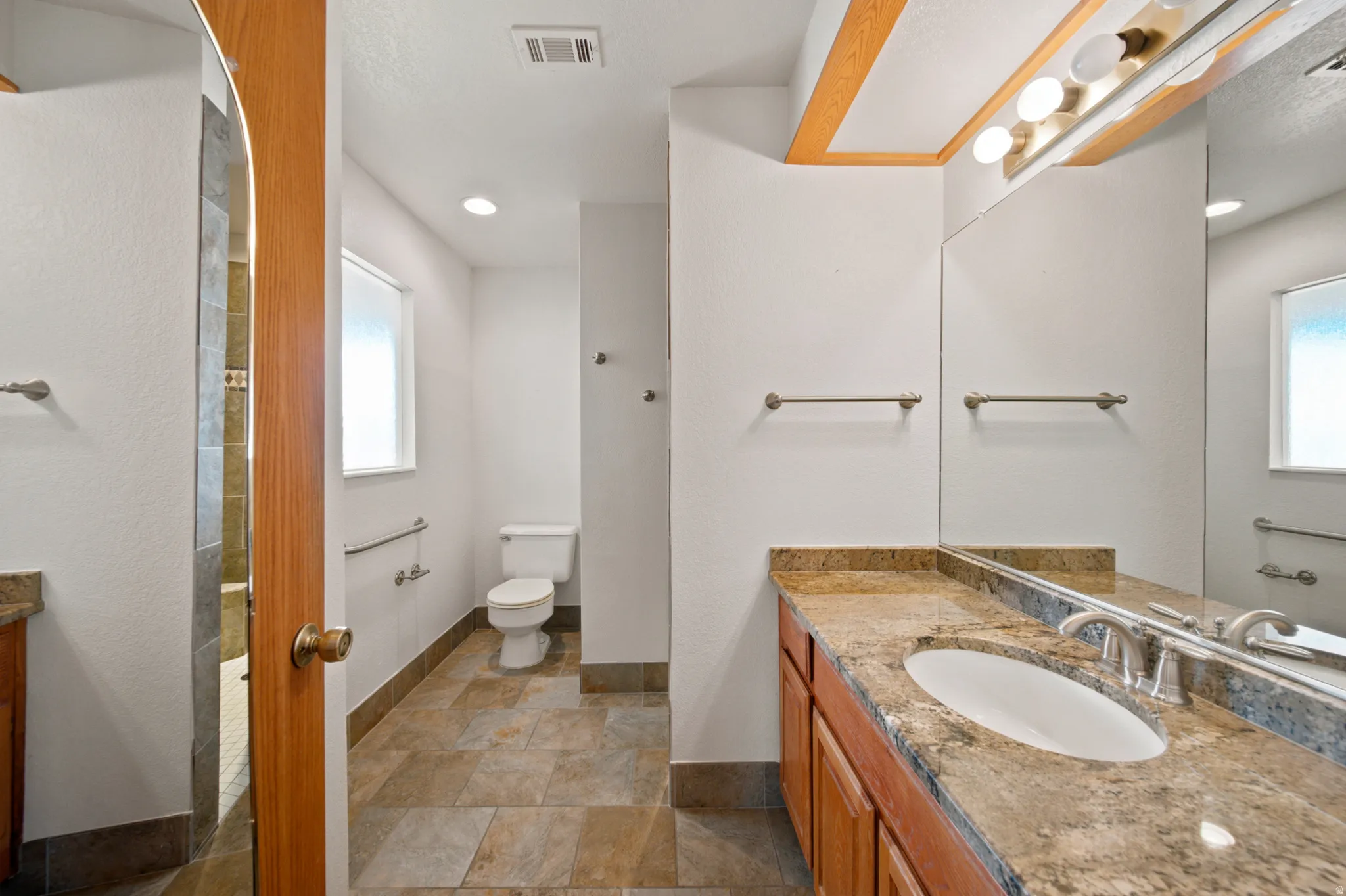 Bathroom featuring a vanity with an integrated sink, stone countertop, and wood-finish cabinetry